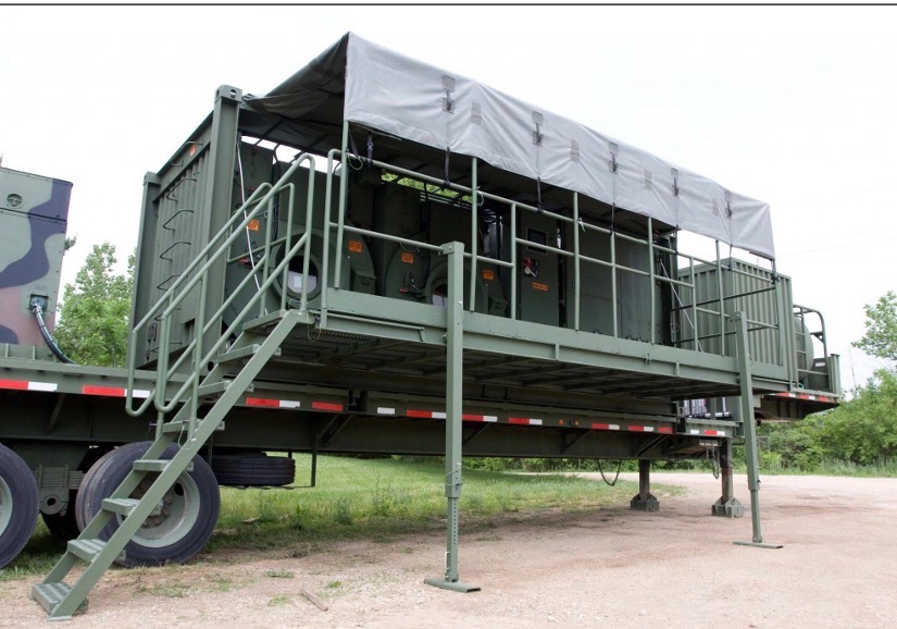 LADS Laundry Advance System protective tarp deployed as waterproof canopy over trailered laundry drums